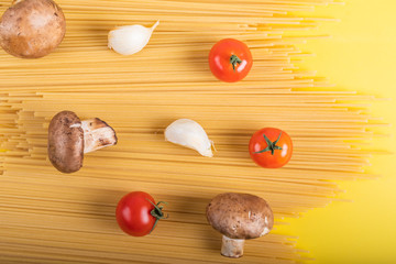 Spaghetti pasta with ingredients for cooking pasta on a yellow background. Colorful top and closeup