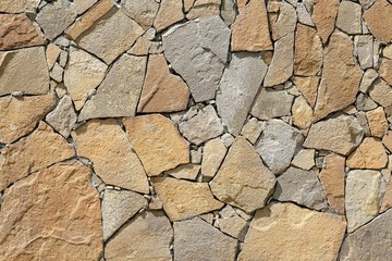 Texture of masonry closeup. Stones of different sizes on the wall, decoration of the facade of the house. Abstract brown rock pattern. Facing the facade of the house with natural stone. Copy space.