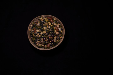 Top down image of a bowl of Indian mixed pulses in a dark copy space background. Food and product photography.
