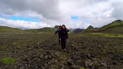 Two young tourists walking through the valley on the 54 km trek from Landmannalaugar, Iceland