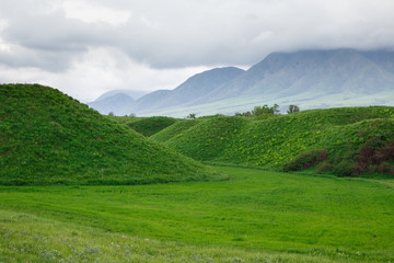 Landscape summer and spring. Bright green grass on the round hills. Clouds before the rain. Clouds...