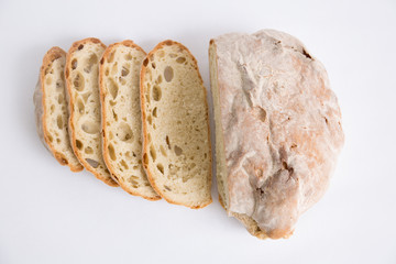 Top view of cut homemade bread loaf and stacked slices. Closeup shot. Isolated object on white background. Homemade food or breakfast concept