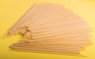 Uncooked yellow long spaghetti on a rustic background. Yellow italian pasta. Long spaghetti.