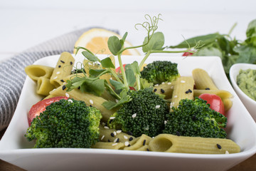 Gluten-free fresh cooked penne pasta from green peas isolated on wooden board. basil