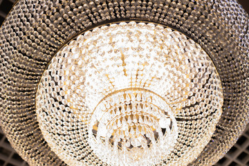 Golden light, a beautiful crystal chandelier with many glass crystals of diamonds shining in the reflected light. Background backdrop wallpaper for design
