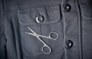 black jacket with large buttons and scissors on the chest pocket