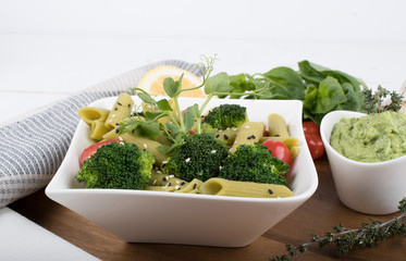Gluten-free fresh cooked penne pasta from green peas isolated on wooden board. basil