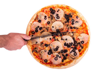 The chef cuts the pizza with a kitchen knife, top view. Delicious pizza with ham, mozzarella, mushrooms and olives, isolated on white background