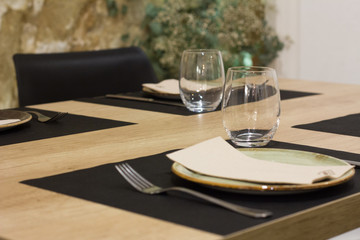 Elegant restaurant table for dinner, with plate and napkins in green colors.