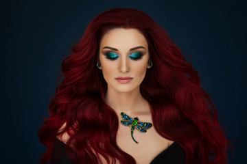 Portrait of a beautiful young red haired girl with with piercings and bright green and blue makeup...