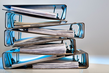 Stack of office folders with archived paperwork in blue light