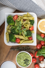 Gluten-free fresh cooked penne pasta from green peas isolated on wooden board. basil
