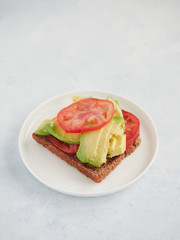avocado and tomato toast, vertical view on a blue surface