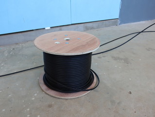 Black internet cable in the wooden coil spool.