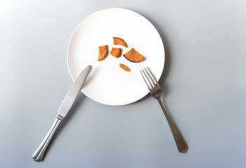 White plate with some crackers, knife and fork, poverty, bankruptcy, hunger, concept picture