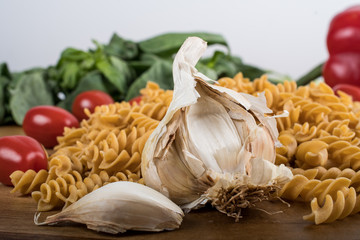 Gluten-free penne pasta from chickpeas, red lentils on wooden cutting board. basil,tomatoes, garlic