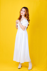 Fototapeta na wymiar Beautuful Asian woman wearing white dress on yellow background.