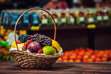 Basket and fresh fruits on wooden table at the market