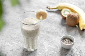 Healthy smoothie made from banana, kiwi and chia seeds on light gray concrete. Vitamin delicious breakfast recipe.