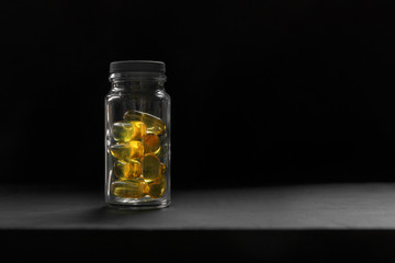 Omega-3 (fish oil capsules) in a glass bottle on a black background. The concept of strengthening health and immunity with vitamins. low key photo