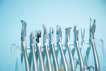 Metal tools for correction of brace systems. Dental tools for the orthodontist. Colored rubber bands for braces. Dental instruments on a blue background in a dental clinic.