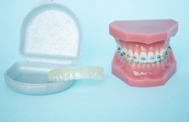 Metal braces for teeth and tools for correction of brace systems. Dental tools for the orthodontist. Colored rubber bands for braces. Correction of a smile at an orthodontist. White aligner
