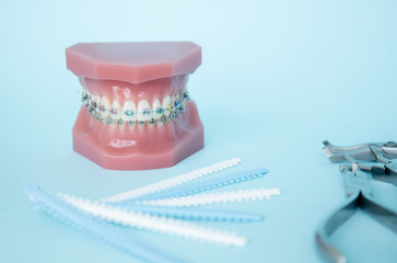 Metal braces for teeth and tools for correction of brace systems. Dental tools for the orthodontist. Colored rubber bands for braces. Dental instruments on a blue background in a dental clinic.