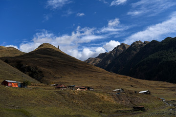 Medieval tower ont the top of a mountain landscape with houses down the valley in Tusheti region