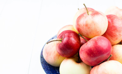 Ripe apples on a plate on a light background, close-up. The harvest of autumn apples. Copy space.