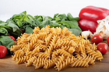 Gluten-free penne pasta from chickpeas, red lentils on wooden cutting board. basil,tomatoes, garlic