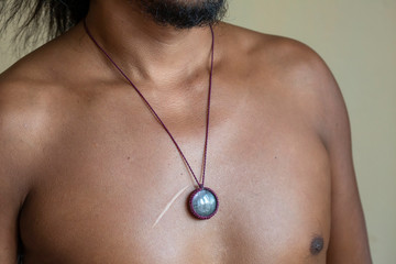 Male chest wearing elegant necklace with natural mineral gemstone