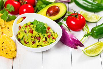 Guacamole Dip with Avocado, Lime, Tomato and Cilantro on Wooden Background. Selective focus.