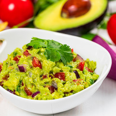 Guacamole Dip with Avocado, Lime, Tomato and Cilantro on Wooden Background. Selective focus.