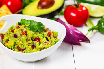 Guacamole Dip with Avocado, Lime, Tomato and Cilantro on Wooden Background. Selective focus.