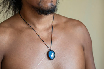 Male chest wearing elegant necklace with natural mineral gemstone