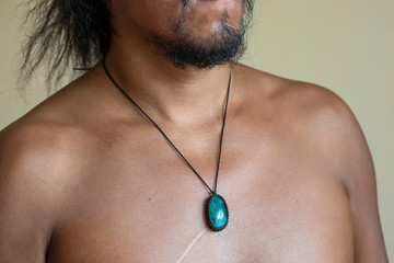 Male chest wearing elegant necklace with natural mineral gemstone