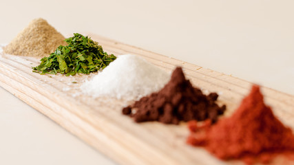 Assortment of spices in line on a wooden board.