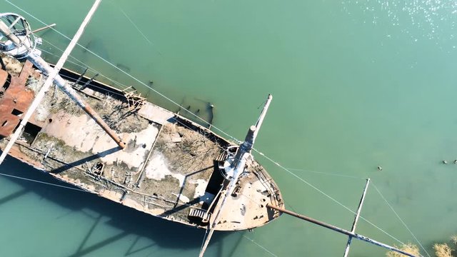 Above a rusty shipwreck, flying at mast level