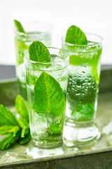 Summer Sweet Refreshing Mint Liqueur Cocktail Shots with Ice and Mint Leaves on White Wooden Background. Selective focus.