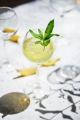 Lemonade or mojito cocktail with lemon and mint, cold refreshing drink or beverage with ice. Homemade limoncello in a glass on a thin leg. A Margarita Cocktail with a lemon slice
