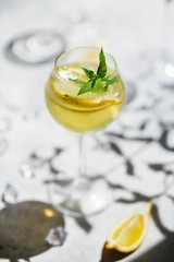 Lemonade or mojito cocktail with lemon and mint, cold refreshing drink or beverage with ice. Homemade limoncello in a glass on a thin leg. A Margarita Cocktail with a lemon slice