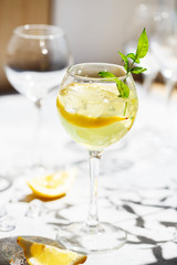 Lemonade or mojito cocktail with lemon and mint, cold refreshing drink or beverage with ice. Homemade limoncello in a glass on a thin leg. A Margarita Cocktail with a lemon slice
