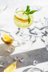 Lemonade or mojito cocktail with lemon and mint, cold refreshing drink or beverage with ice. Homemade limoncello in a glass on a thin leg. A Margarita Cocktail with a lemon slice