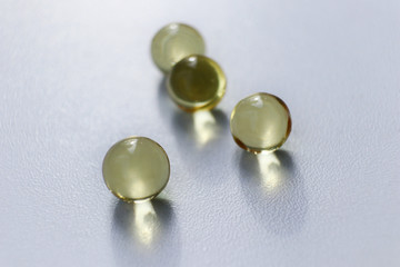 Transparent round capsules of vitamins - Fish oil pills close-up. Small gold-yellow balls on a white background. Concept of treatment and prevention of health. 