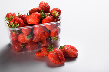 fresh organic strawberries in a plastic box on a white background. delivery of organic products. packaging of organic strawberries.