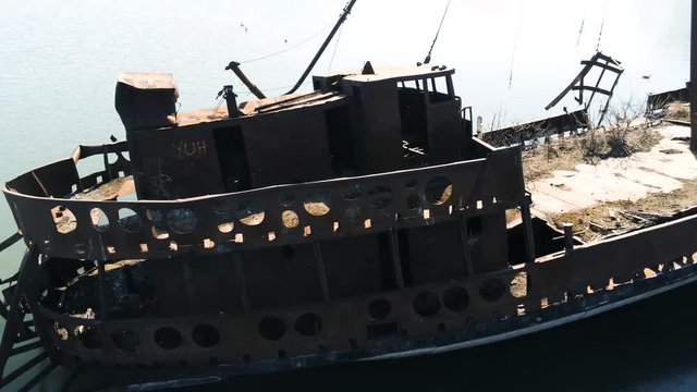 Flyby along side a rusty sunken ship where geese are nesting