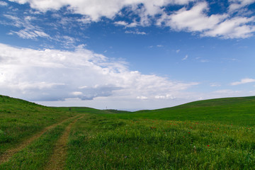 Beautiful spring and summer landscape. Mountain country road among green hills. Lush green hills, high mountains. Spring flowering grass.
