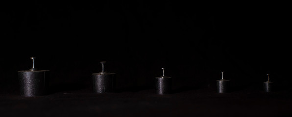 Different weights are arranged at a distance to represent social distancing in a dark copy space background. Product photography.