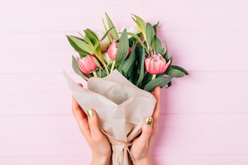 Top view of female hands holding lush bouquet of tulips