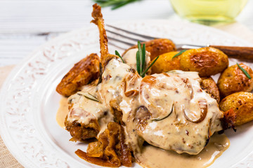 Fried Rabbit Meat With Rosemary in Sour Cream Sauce and Potato on White Wooden Background. Selective focus.